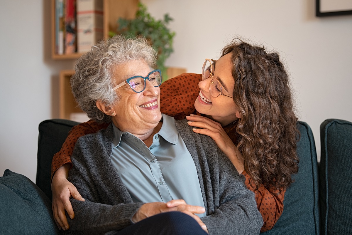 Grandmother and granddaughter laughing and embracing at home adult daughter hugging grandma